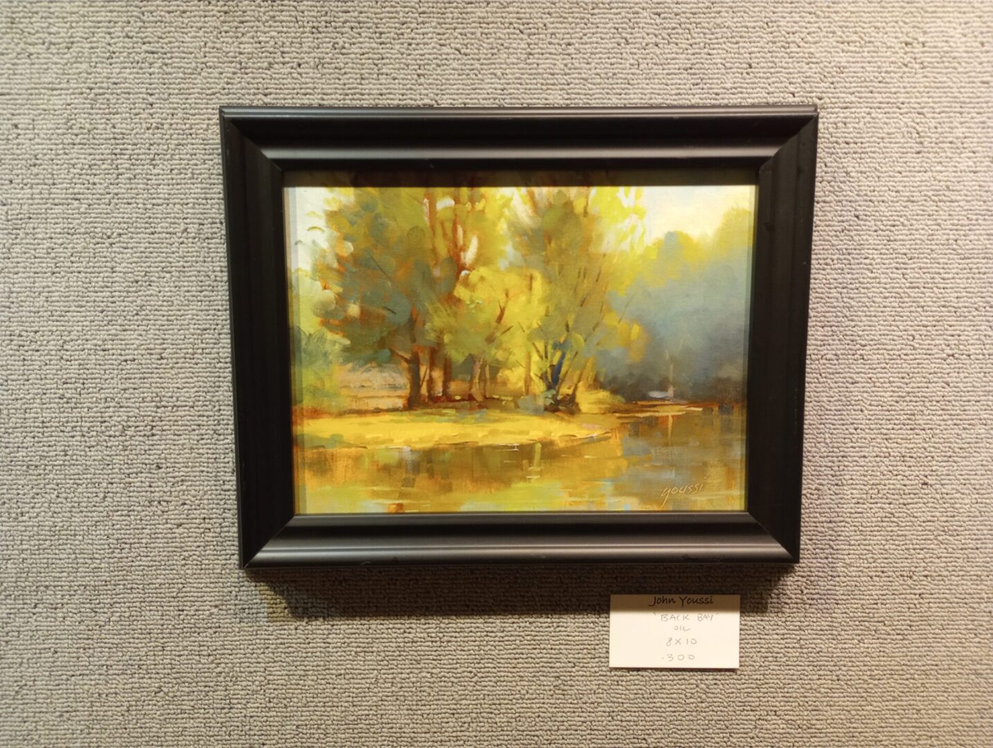 A framed painting of trees on a wall.